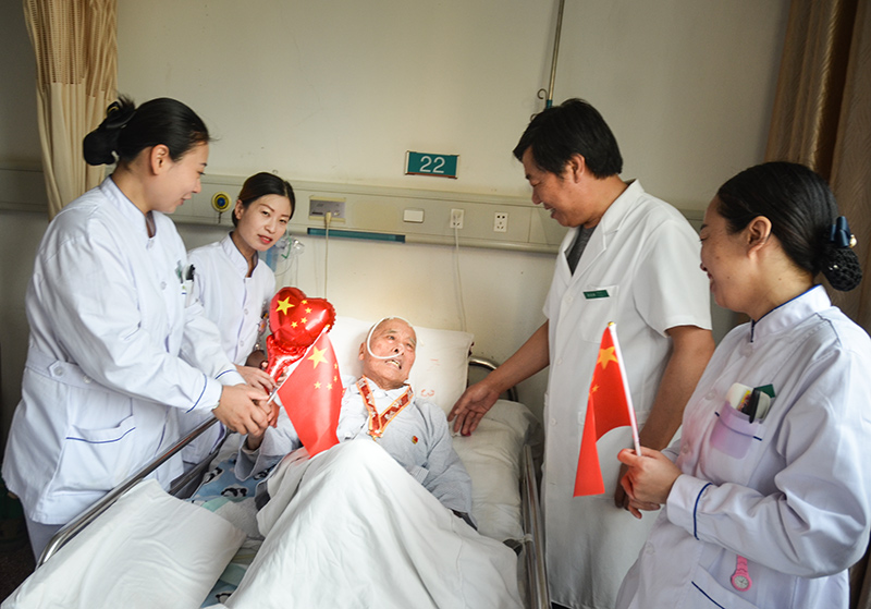 4峰峰總醫院國慶節當日內三科病房里醫護們為93歲的患者秦武平帶上中共中央、國務院中央軍委頒發的國慶70周年紀念章并和他一起歡度國慶，秦爺爺曾參加過南征北戰、孟良崮戰役、淮海戰役、抗美援朝是一名老軍人、老革命 作者：肖建華(2).jpg
